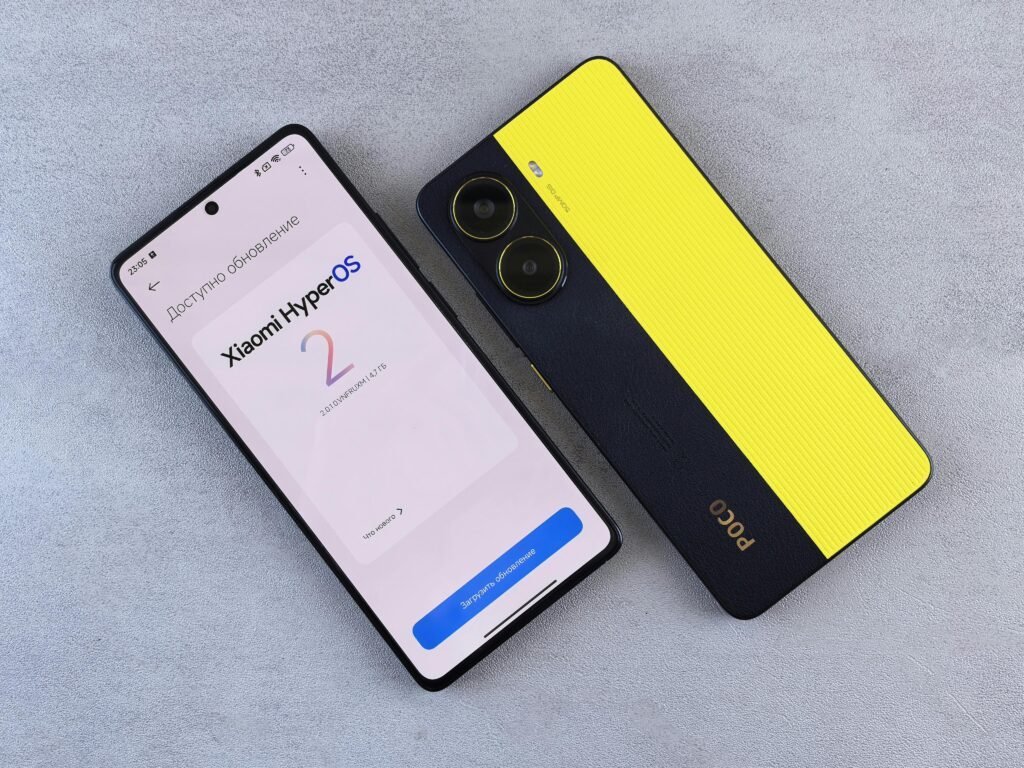 Top view of two smartphones displaying Xiaomi HyperOS update screen and POCO branding on a plain surface.